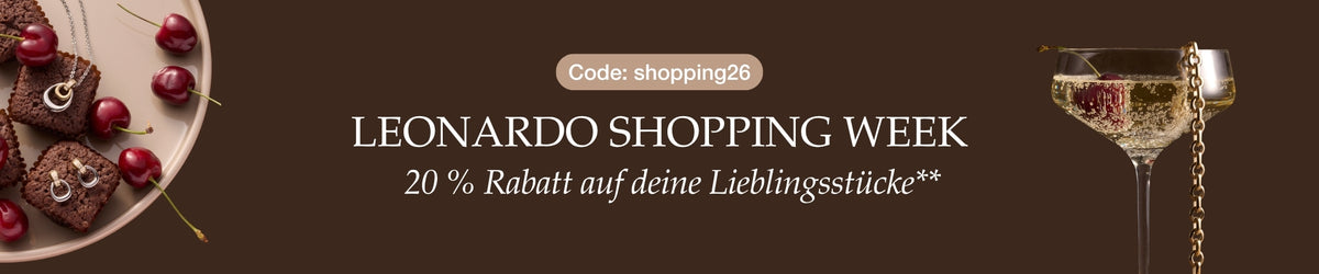 Leonardo Shopping Week, 20 % Rabatt auf deine Lieblingsstücke, Code: shopping26. Festliche Dekoration mit roten Kugeln, Geschenkboxen, Champagnerglas und Schmuckkette auf braunem Hintergrund
