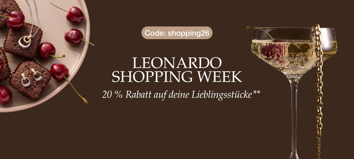Leonardo Shopping Week, 20% Rabatt auf deine Lieblingsstücke, Code: shopping26. Schokoladenkuchen mit Kirschen, Champagnerglas und goldene Kette auf braunem Hintergrund