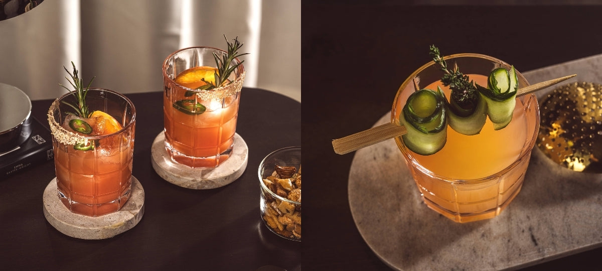 Cocktails in strukturierten Gläsern werden stimmungsvoll inszeniert, dekoriert mit Kräutern, Gurke und Früchten.