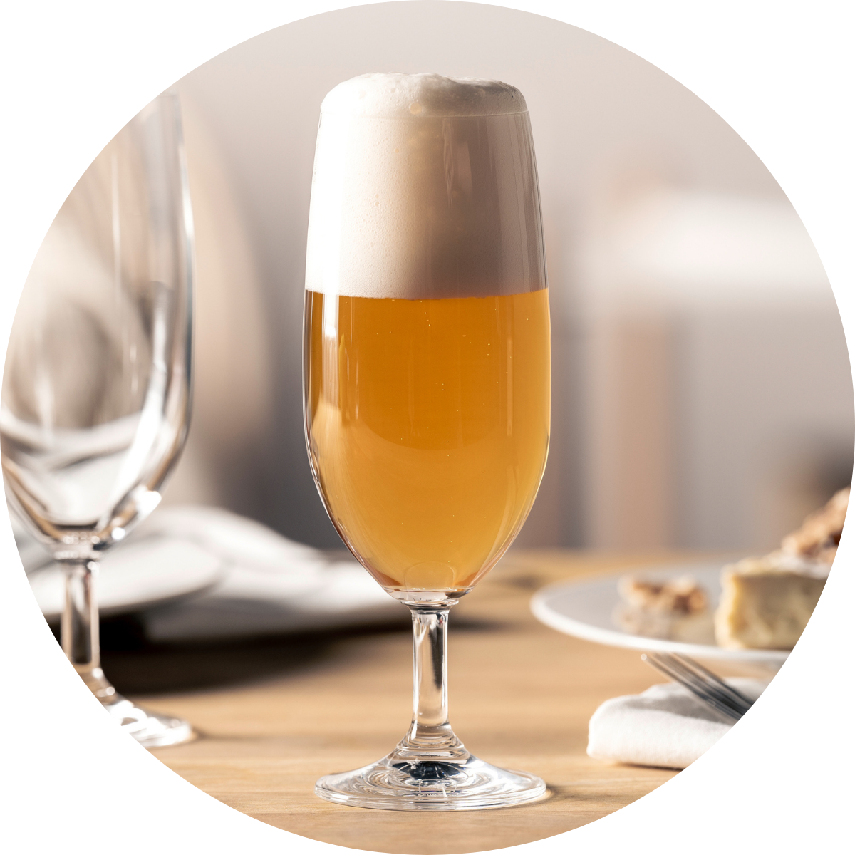 Stilvoll serviertes Helles Bier mit üppiger Schaumkrone in einem eleganten Bierglas auf einem gedeckten Tisch.